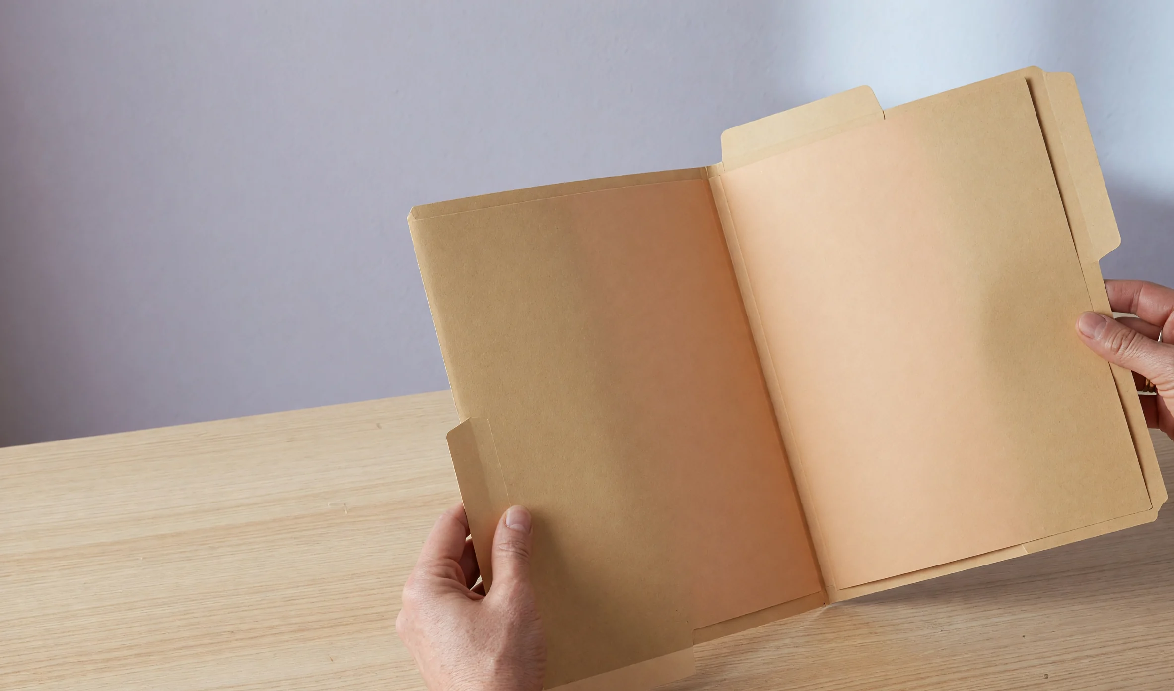 Open blank manila folder held over a pale oak desk Open blank manila folder held over a pale oak desk