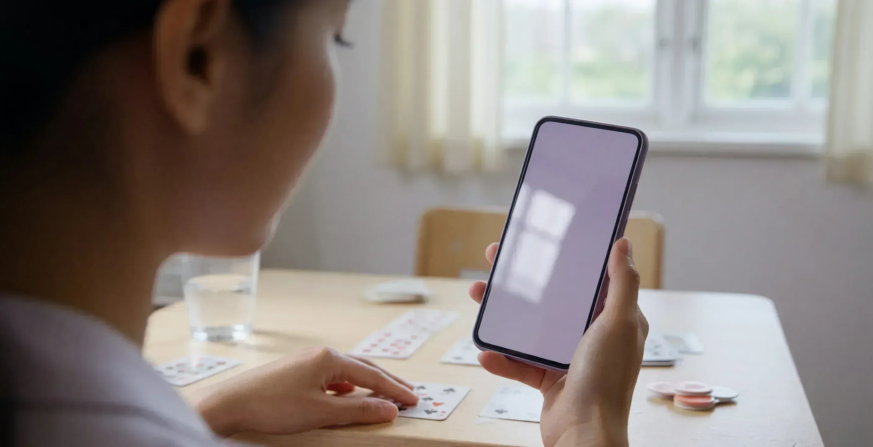 Standing view of a rummy table with a blank notebook and face-down phone